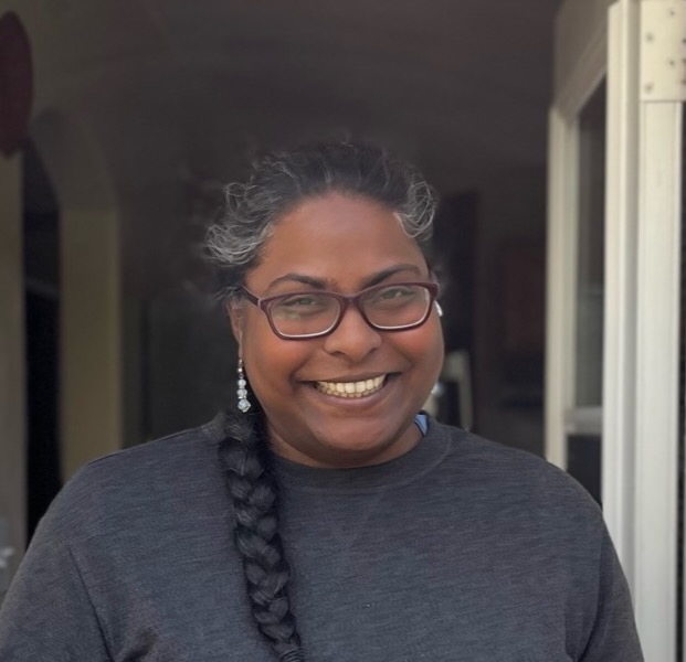 Rebecca smiling, wearing glasses, with a long braid